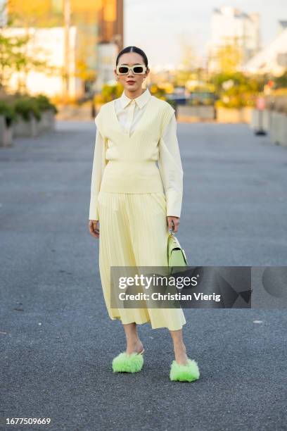 Guest wears yellow pleated skirt, top outside COS on September 12, 2023 in New York City.