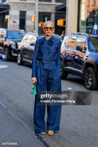 Caroline Caro Daur wears blue pants, button shirt with tie, mint green Hermes bag, sunglasses outside Carolina Herrera on September 12, 2023 in New...