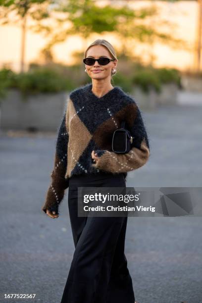 Claire Rose Cliteur wears brown black beige cashmere jumper, black wide leg pants, red heels, bag, sunglasses outside COS on September 12, 2023 in...