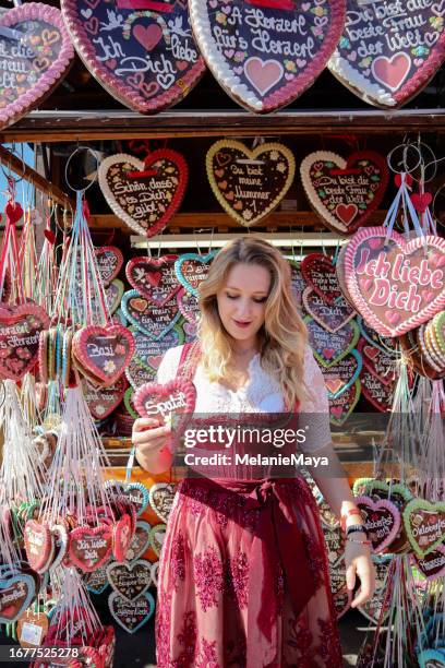 mulher loira no vestido dirndl comprando lembrança do coração de gengibre no festival de cerveja alemão - saia tipo camponesa com ou sem corpete - fotografias e filmes do acervo