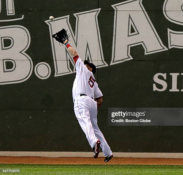 Boston Red Sox left fielder Jonny Gomes makes a lunging defensive catch of a deep drive to left by Houston Astros center fielder Robbie Grossman in...