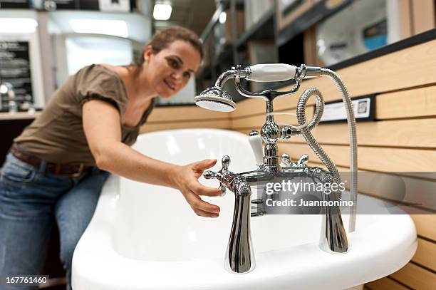 woman testing bathtub tap in store - sink plug stock pictures, royalty-free photos & images