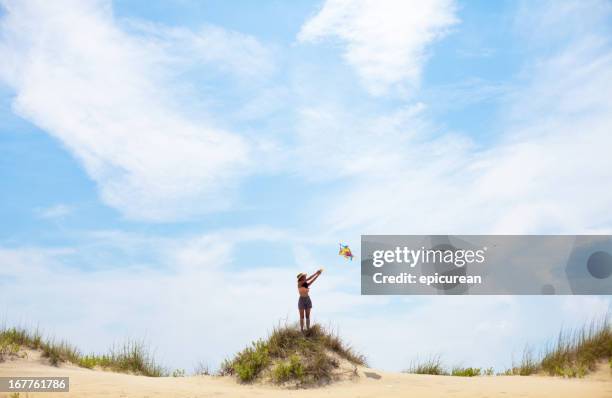 young woman flying kite on summery day at the beach - people flying kites stockfoto's en -beelden