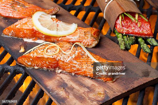 drei gegrillte lachs-filets auf zedernholz - gegrillter lachs stock-fotos und bilder