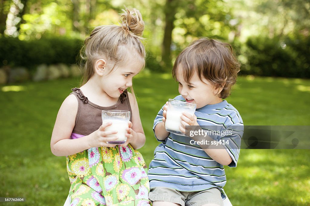 Two Little Kids Drinking Milk While Outdoors