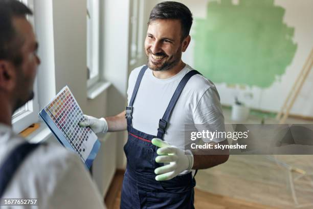 happy house painter talking to his colleague about colors during home renovation process. - decorating stock pictures, royalty-free photos & images