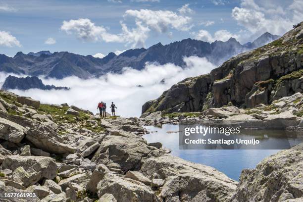hikers arriving at embarrat lakes in pyrenees national park - cauterets stockfoto's en -beelden