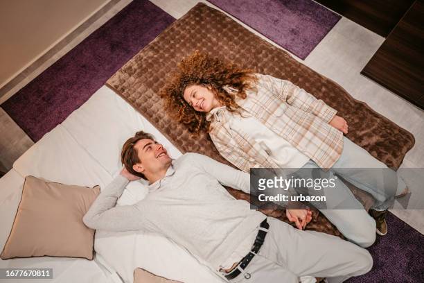 young couple lying on the bed in a hotel room - escape the room event stock pictures, royalty-free photos & images