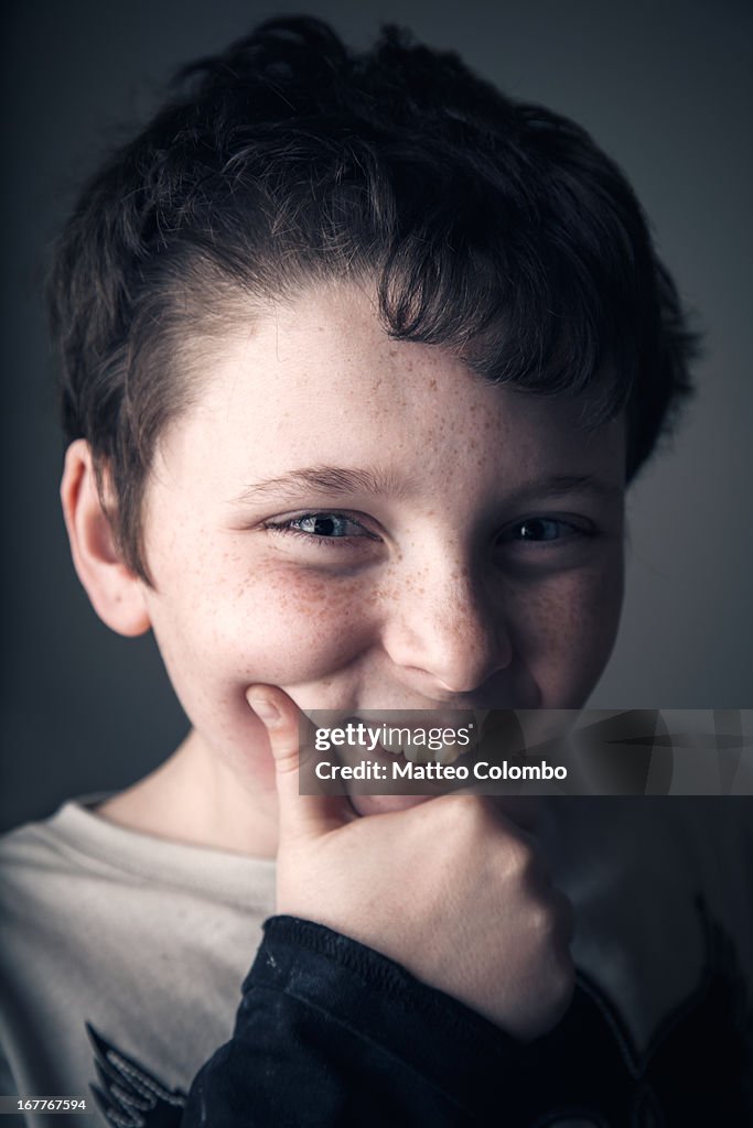 Studio portrait of smiling child holding his chin