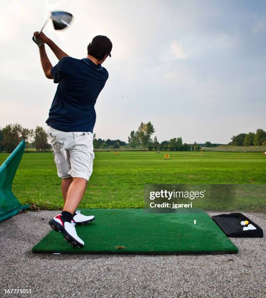 golfer teeing off at a driving range - driving range stock pictures, royalty-free photos & images