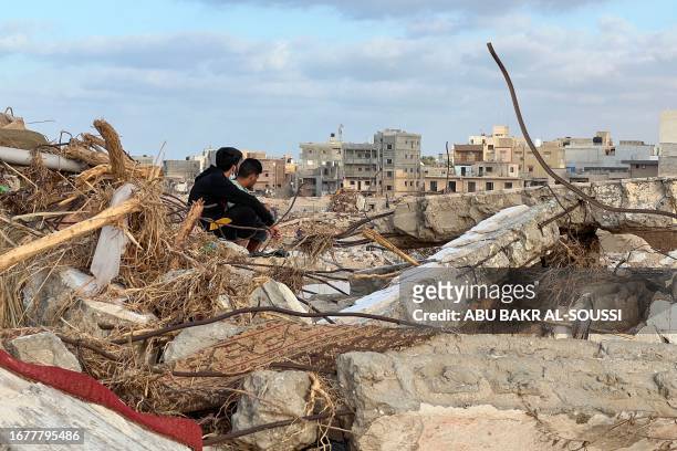 People sit among the rubble in Libya's eastern city of Derna on September 20 following a deadly flash flood. Ten days after a tsunami-scale flash...