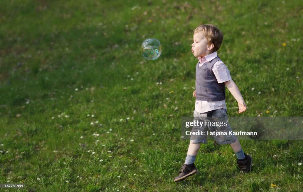 Boy runs after a big soap bubble