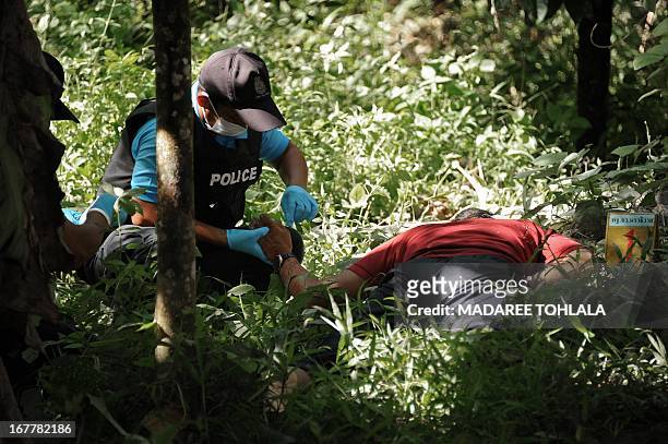 Thai police officers inspect the body of a suspected separatist militant who was shot dead during a clash with army rangers in the Cha-nea district...