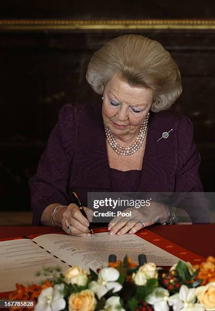 Queen Beatrix of the Netherlands signs the Act of Abdication during a ceremony in the Moseszaal at the Royal Palace on April 30, 2013 in Amsterdam....