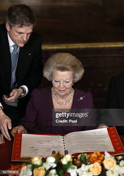 Queen Beatrix of the Netherlands looks over the Act of Abdication during a ceremony in the Moseszaal at the Royal Palace on April 30, 2013 in...