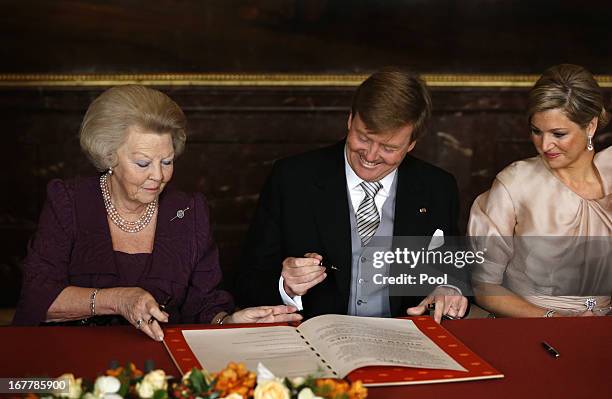 Queen Beatrix of the Netherlands passes the Act of Abdication to her son Prince Willem-Alexander of the Netherlands to sign as his wife Princess...