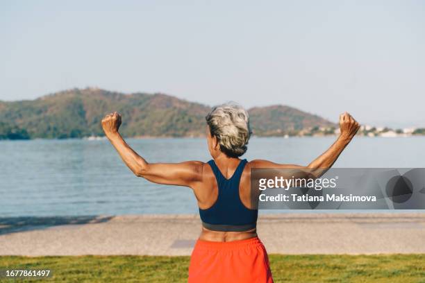 senior gray-haired woman doing exercises in public park, sunny summer morning. - acrobat stock pictures, royalty-free photos & images