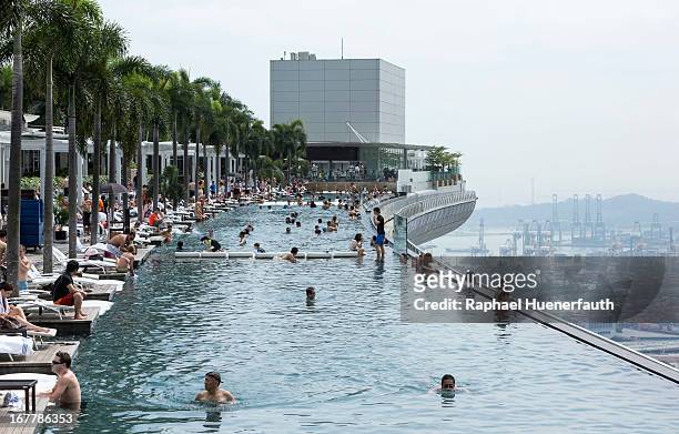 Tourists in the swimming pool on the roof garden of the Marina Bay Sands Resort, with a view of the harbor in the background on February 09, 2013 in...