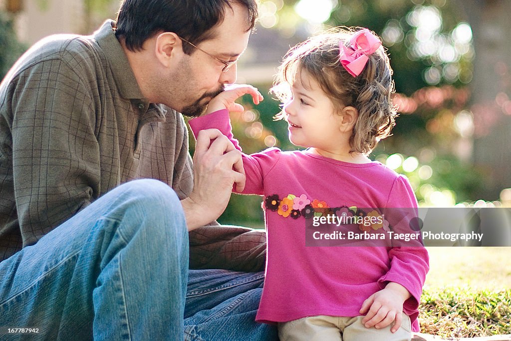 Father kissing young daughter's hand