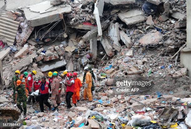 Members of the Bangladeshi Army carry the body of a garment worker, as heavy equipment is brought in to remove debris following the collapse of the...