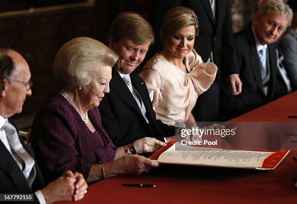 Queen Beatrix of the Netherlands passes the Act of Abdication to her son Prince Willem-Alexander of the Netherlands to sign as his wife Princess...