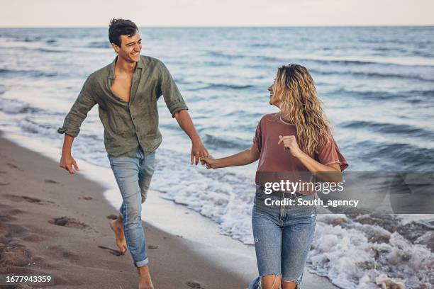 couple walking on the beach - young couple beach stock pictures, royalty-free photos & images