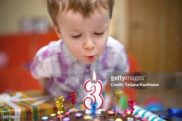little boy blowing out candle on his birthday - 1 1 3 stock-fotos und bilder