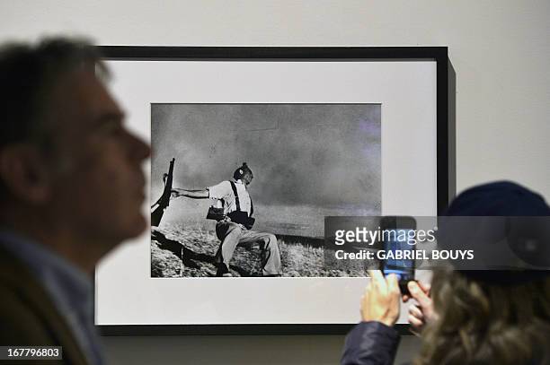 Visitor takes a snapshot of Robert Capa's “The falling soldier, Spain, 1936” during the 'Life. I grandi fotografi" exhibition at the auditorium on...