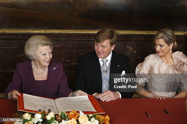 Queen Beatrix of the Netherlands signs the Act of Abdication as her son Prince Willem-Alexander of the Netherlands and his wife Princess Maxima of...