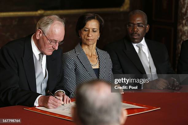 Johan Remkes signs the Act of Abdication as Sarah Wescot-Williams and Rodolphe Samuel during a the ceremony in the Moseszaal at the Royal Palace on...