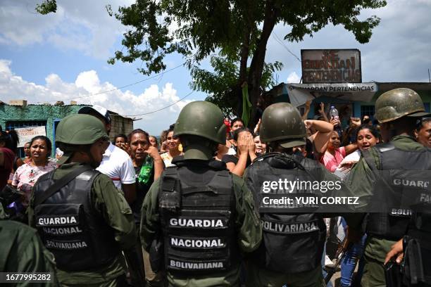 Members of the Bolivarian National Guard stand guard as relatives wait for news after authorities seized control of the Tocoron prison in Tocoron,...