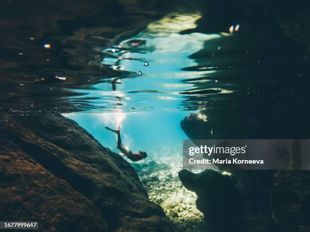 a man swims underwater in the sea in a cave. - freitauchen stock-fotos und bilder