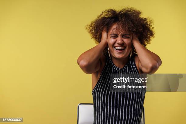 young woman covering her ears due to loud noise - handen over de oren stockfoto's en -beelden