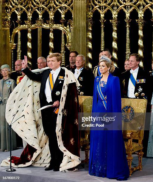 King Willem Alexander of the Netherlands takes the oath as HM Queen Maxima of the Netherlands looks on near members of the royal household during...