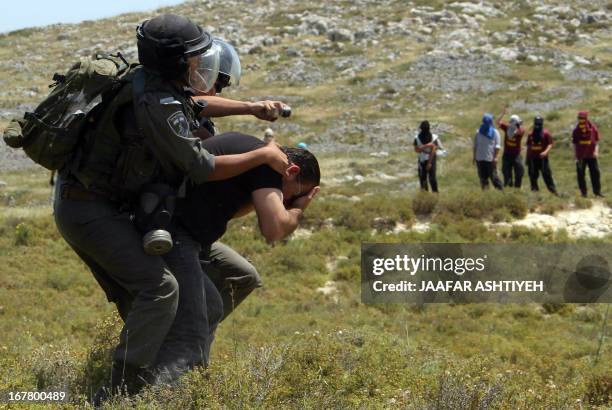 Israeli security forces scuffle with a Palestinian man as Israeli settlers watch on during clashes in the West Bank village of Urif, near Nablus, on...