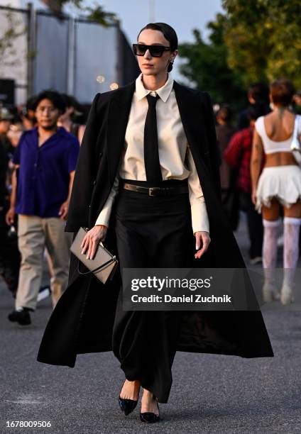 Mary Leest is seen wearing a black Cos blazer, pants, yellow button down shirt and black tie with black sunglasses and a black clutch outside the Cos...