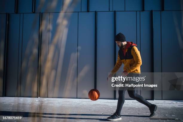 side view of young man playing basketball in city. - street side view photos et images de collection