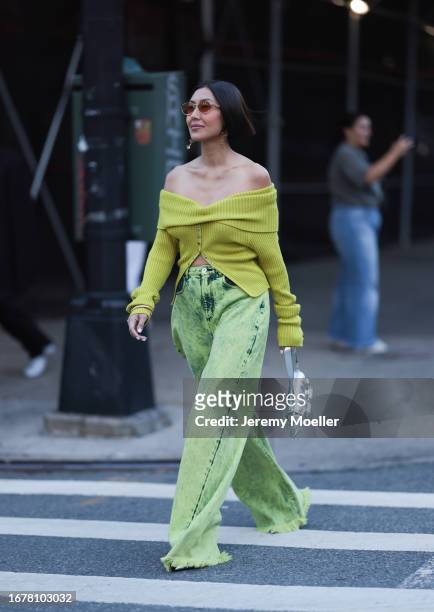 Fashion Show guest was seen wearing an oversized green jeans with fringes on its end, a silver and shiny Gucci Horsebit bag as well as a green half...
