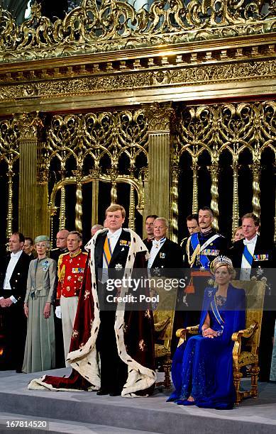 King Willem-Alexander of the Netherlands stands beside the seated HM Queen Maxima of the Netherlands during their inauguration ceremony at New Church...