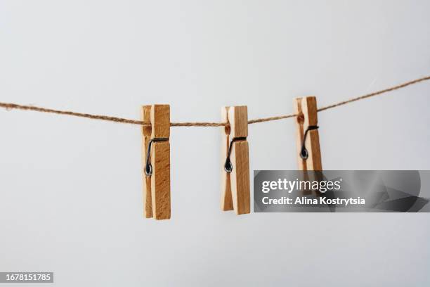 wooden clothespins hang on rope on gray background - 洗濯バサミ ストックフォトと画像