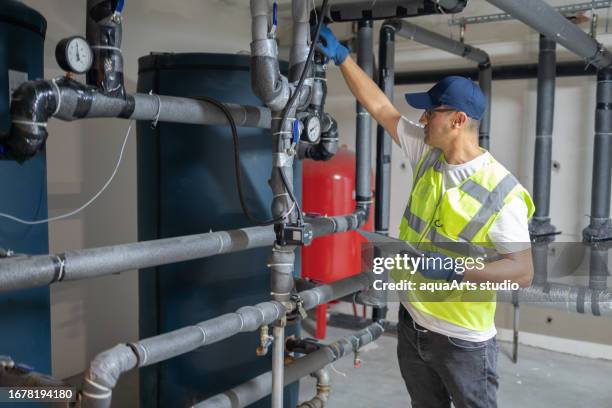 männlicher ingenieur überprüft kesselsystem in einem keller - reparatur handwerker männlich stock-fotos und bilder
