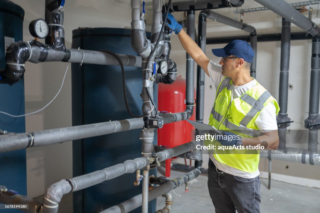 Male Engineer Checking Boiler System In A Basement