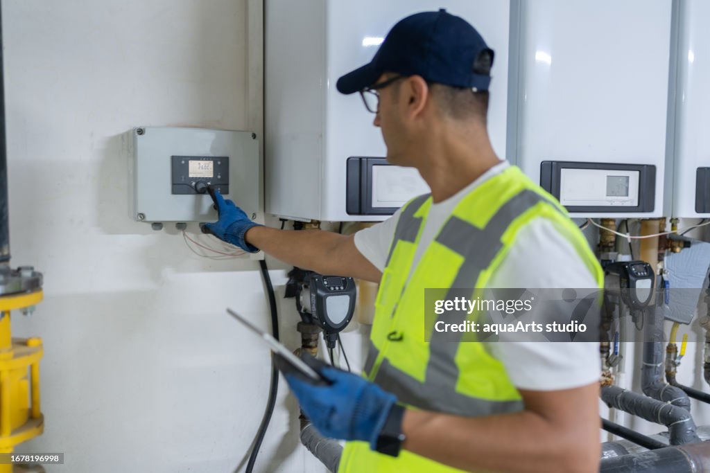 Männlicher Ingenieur überprüft Kesselsystem In Einem Keller