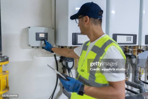 male engineer checking boiler system in a basement - house warm heating oil stockfoto's en -beelden