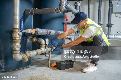 Male Engineer Checking Boiler System In A Basement Male Engineer Checking Boiler System In A Basement