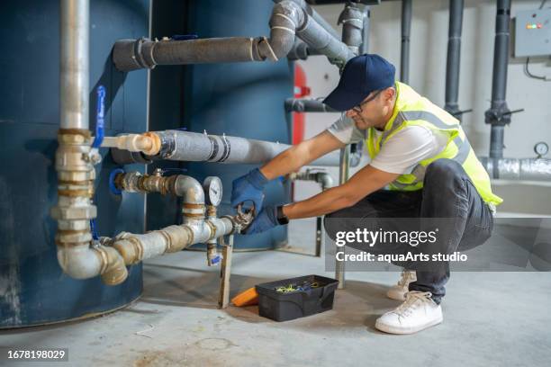 male engineer checking boiler system in a basement - arts plumbing stock pictures, royalty-free photos & images