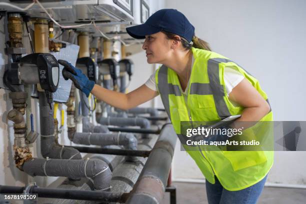 female engineer checking boiler system in a basement - house warm heating oil stockfoto's en -beelden