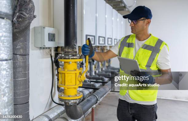 engenheiro masculino verificando o sistema de caldeira em um porão - engenheiro de aquecimento - fotografias e filmes do acervo