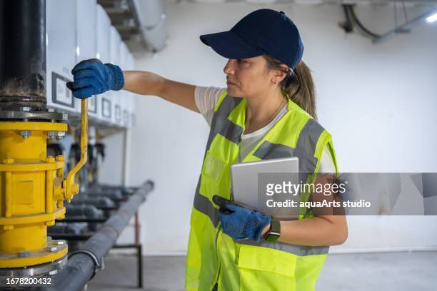 female engineer checking boiler system in a basement - house warm heating oil stockfoto's en -beelden