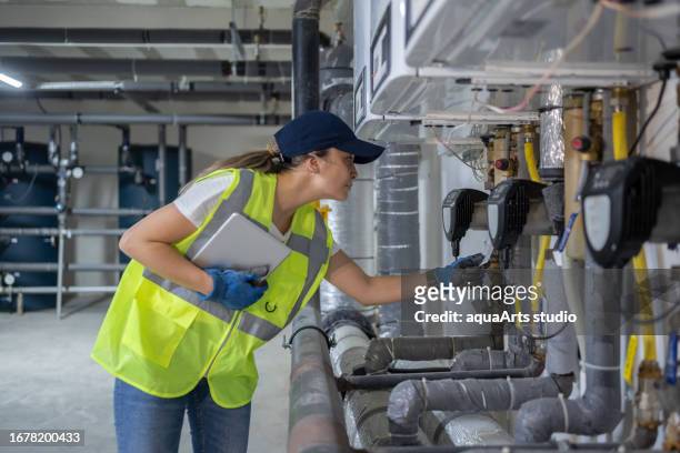 female engineer checking boiler system in a basement - gas engineer stock pictures, royalty-free photos & images